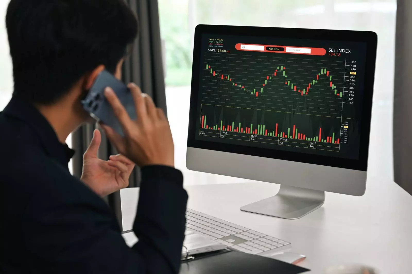 Back View Of Young Businessman Having Phone Conversation And Monitoring Stocks Data Candle Charts On Screen