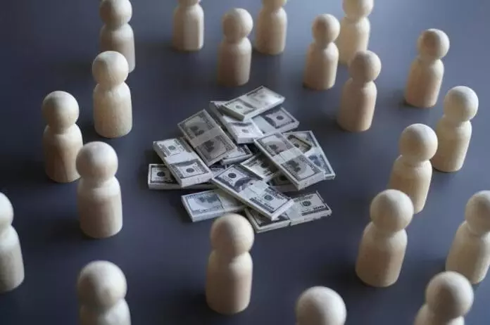 Wooden pawns encircling a stak of play dollar money